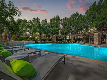 A swimming pool with chairs and tables next to it